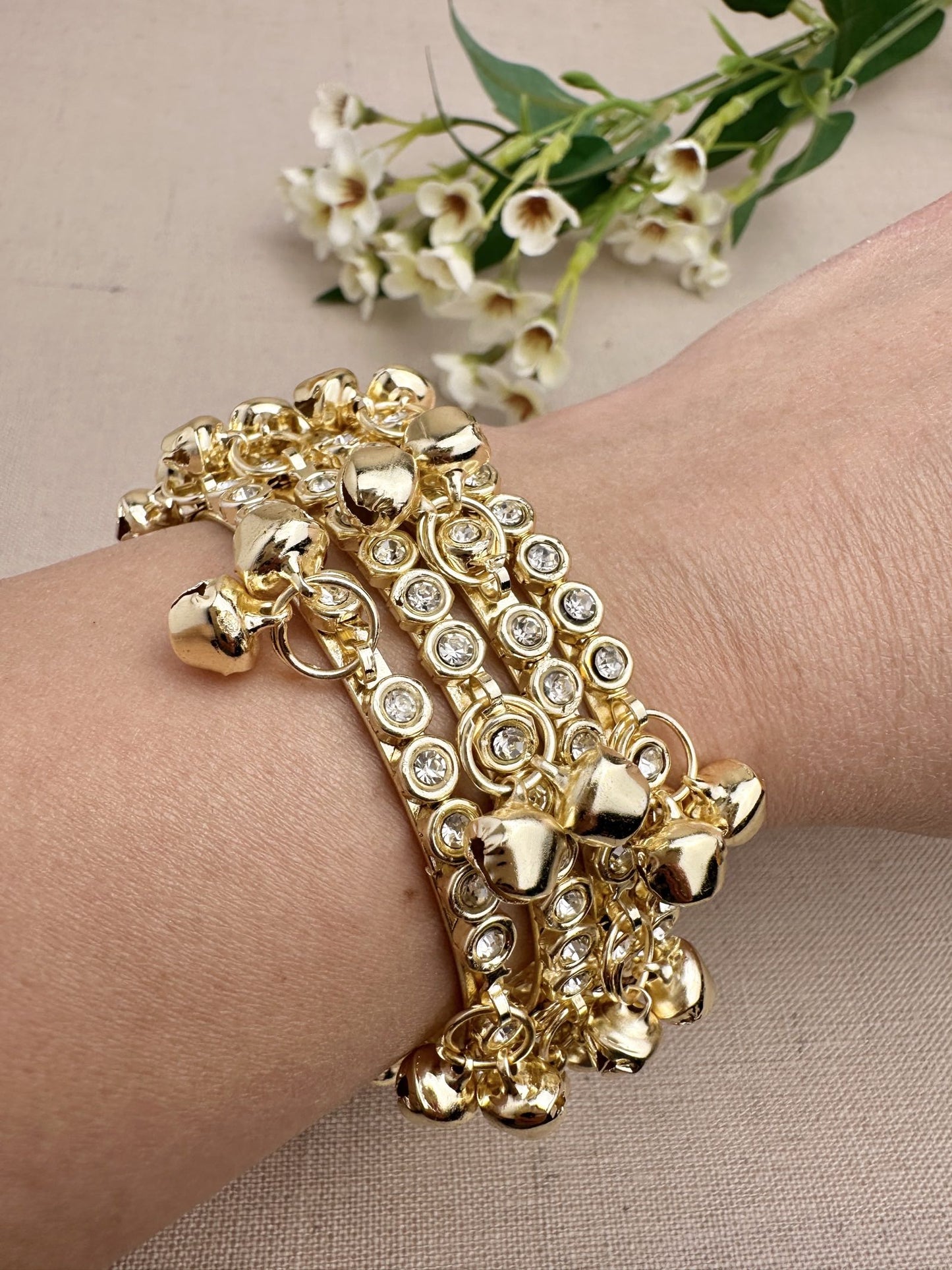 Four gold tone stone ghungroo bangles styled together on wrist