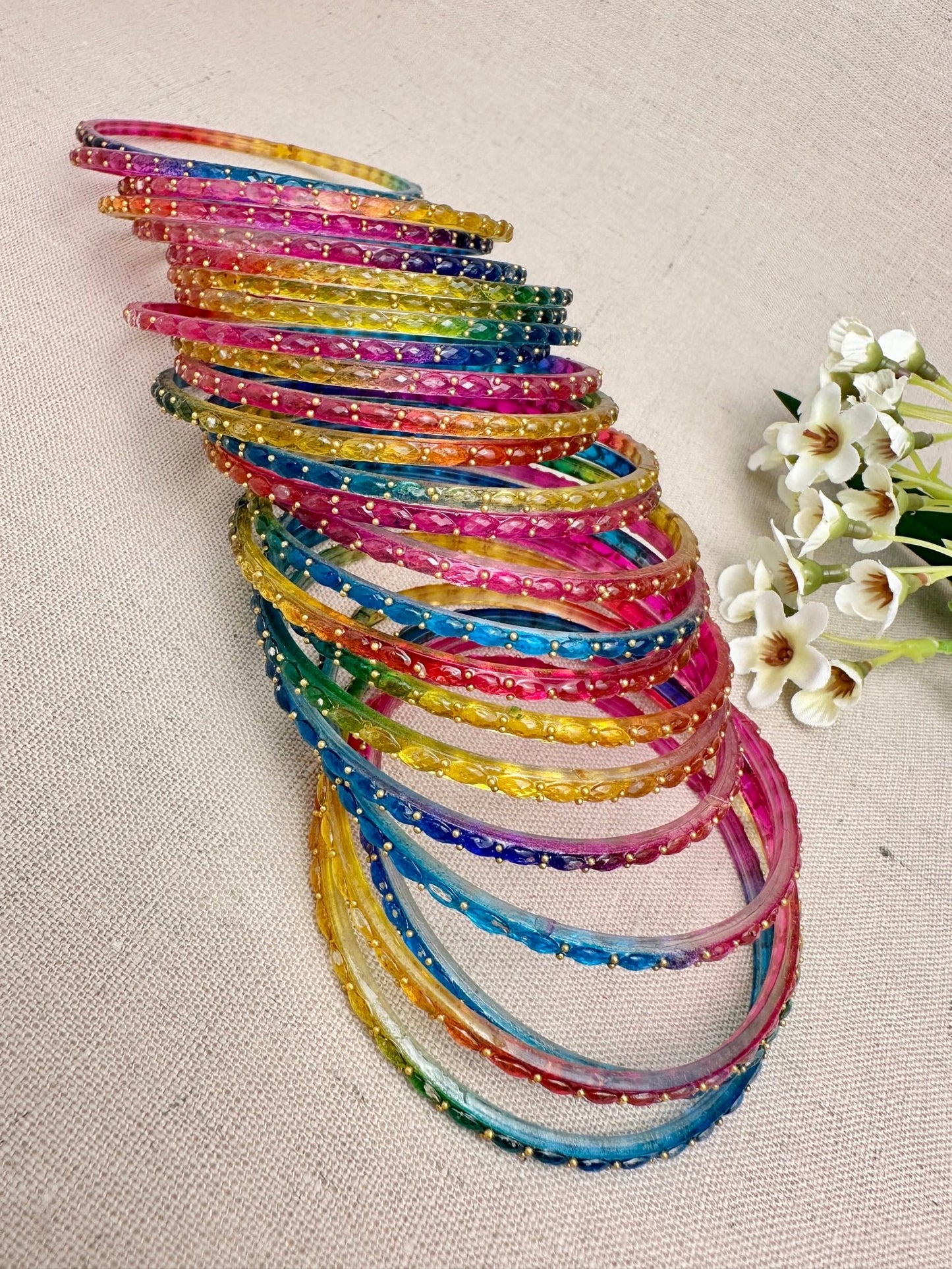 Stacked view of colourful Water Drop glass bangles in a set of 24