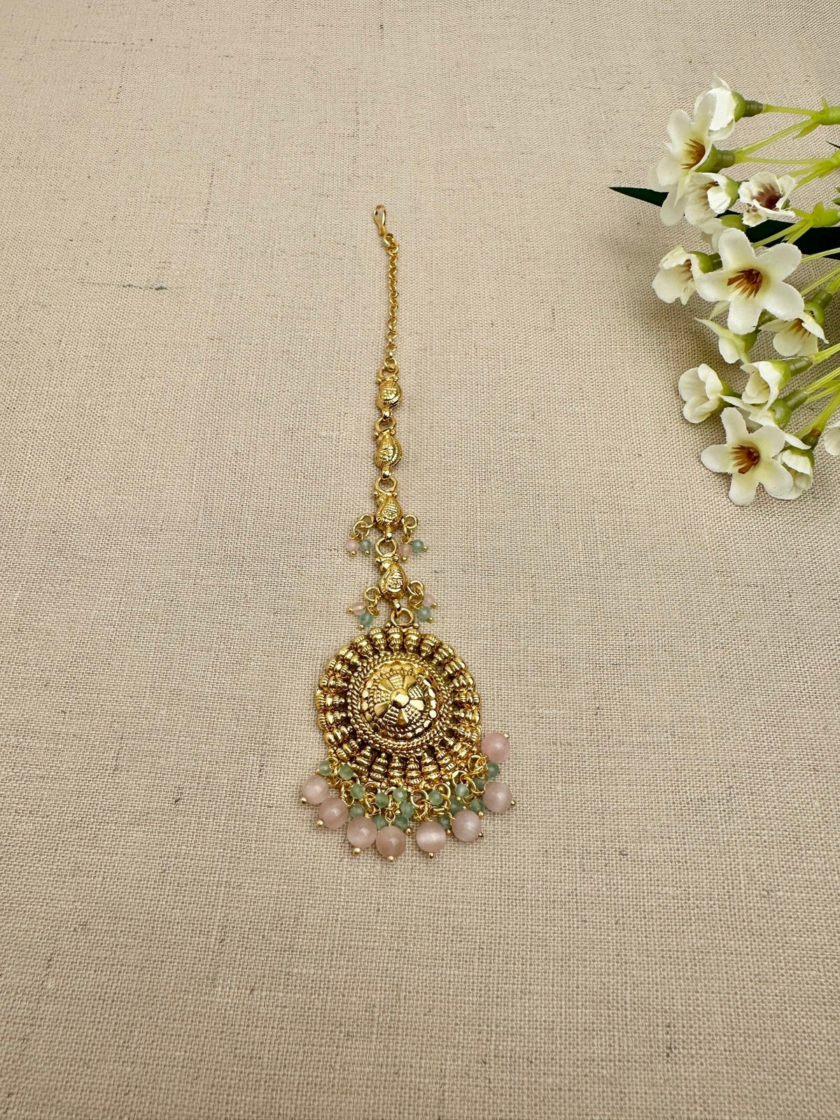 Close-up of the Aarohi Gold-Plated Punjabi maang tikka with pink and mint bead detailing.