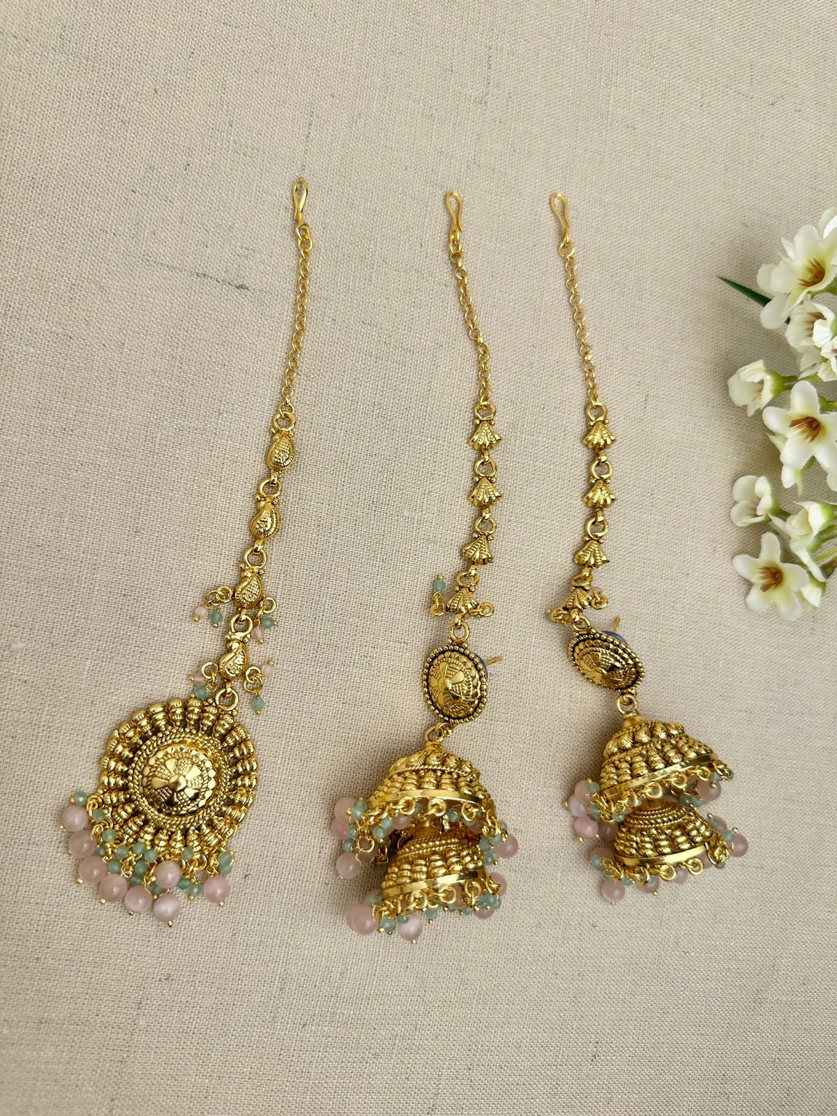 Flat lay of the Aarohi Gold-Plated Punjabi Jhumki AND Tikka Set showing earrings, sahara chains and matching maang tikka.