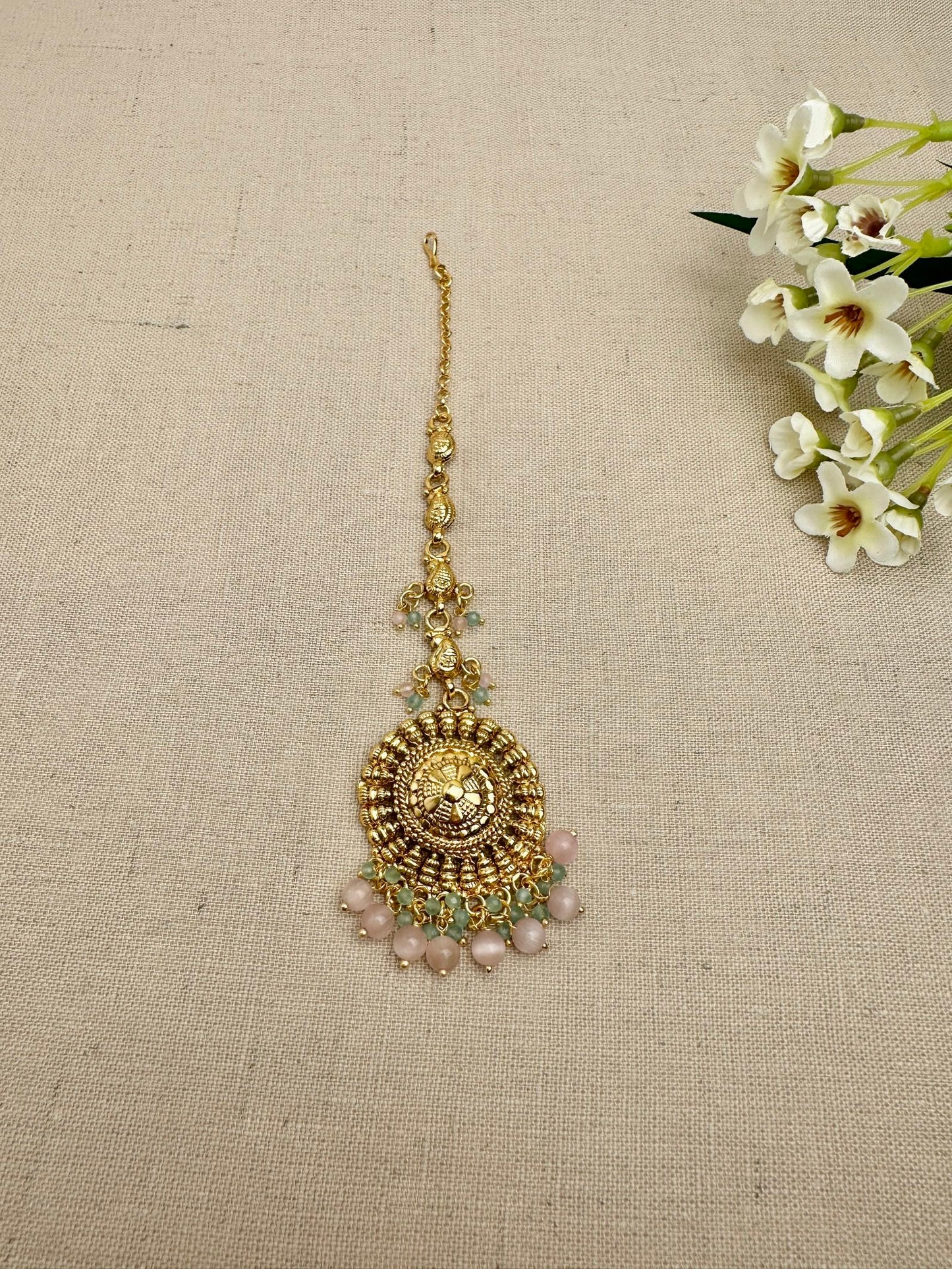Close-up of the Aarohi Gold-Plated Punjabi maang tikka with pink and mint bead detailing.