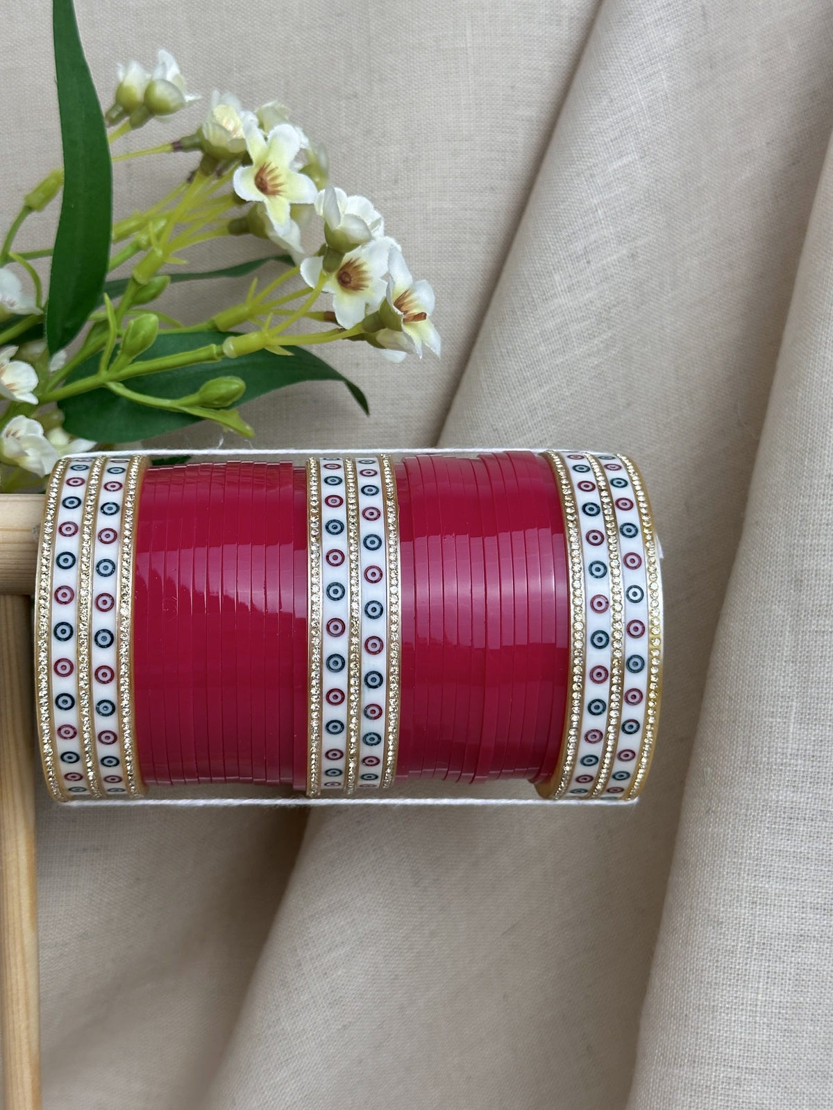 Close-up of hot pink bridal bangles with white patterned bangles, stone borders and gold-toned detailing.