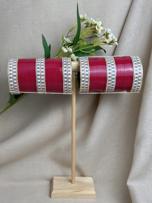 Complete hot pink Punjabi bridal chooda set for both arms displayed on a wooden stand.