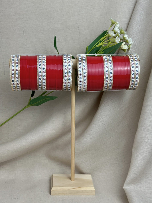 Complete red Punjabi bridal chooda set for both arms displayed on a wooden stand.
