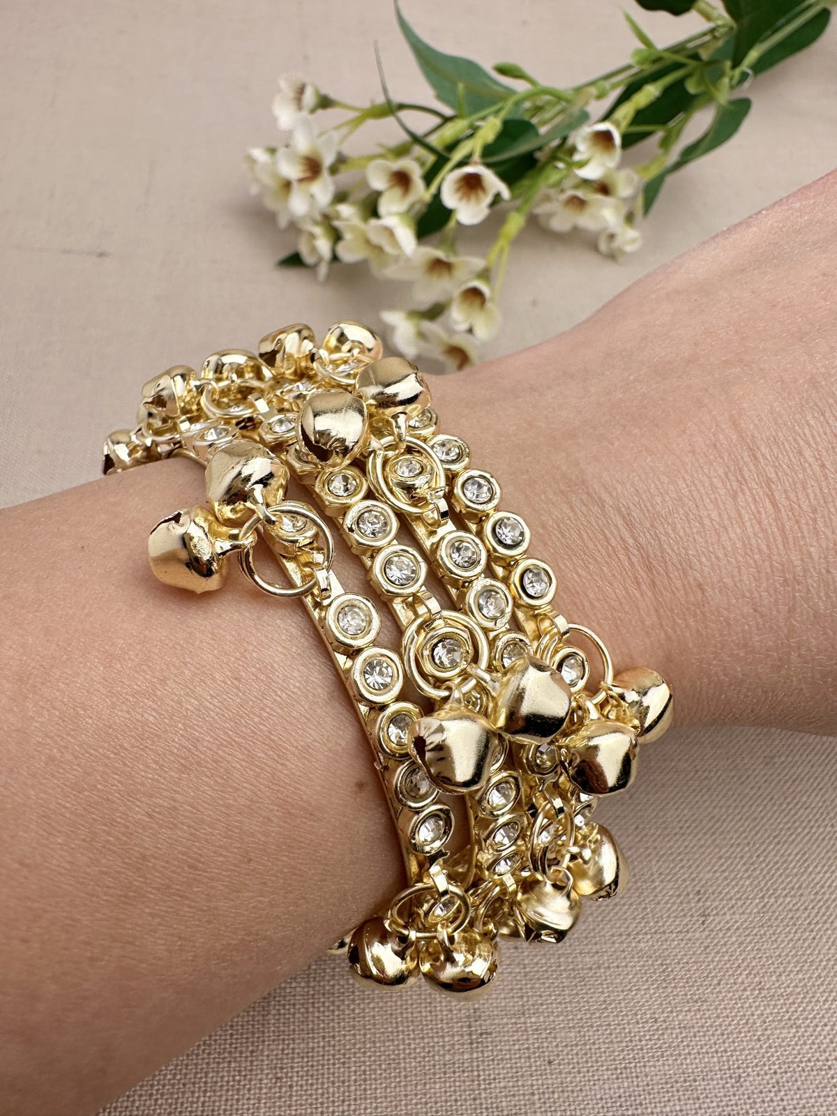 Four gold tone stone ghungroo bangles styled together on wrist