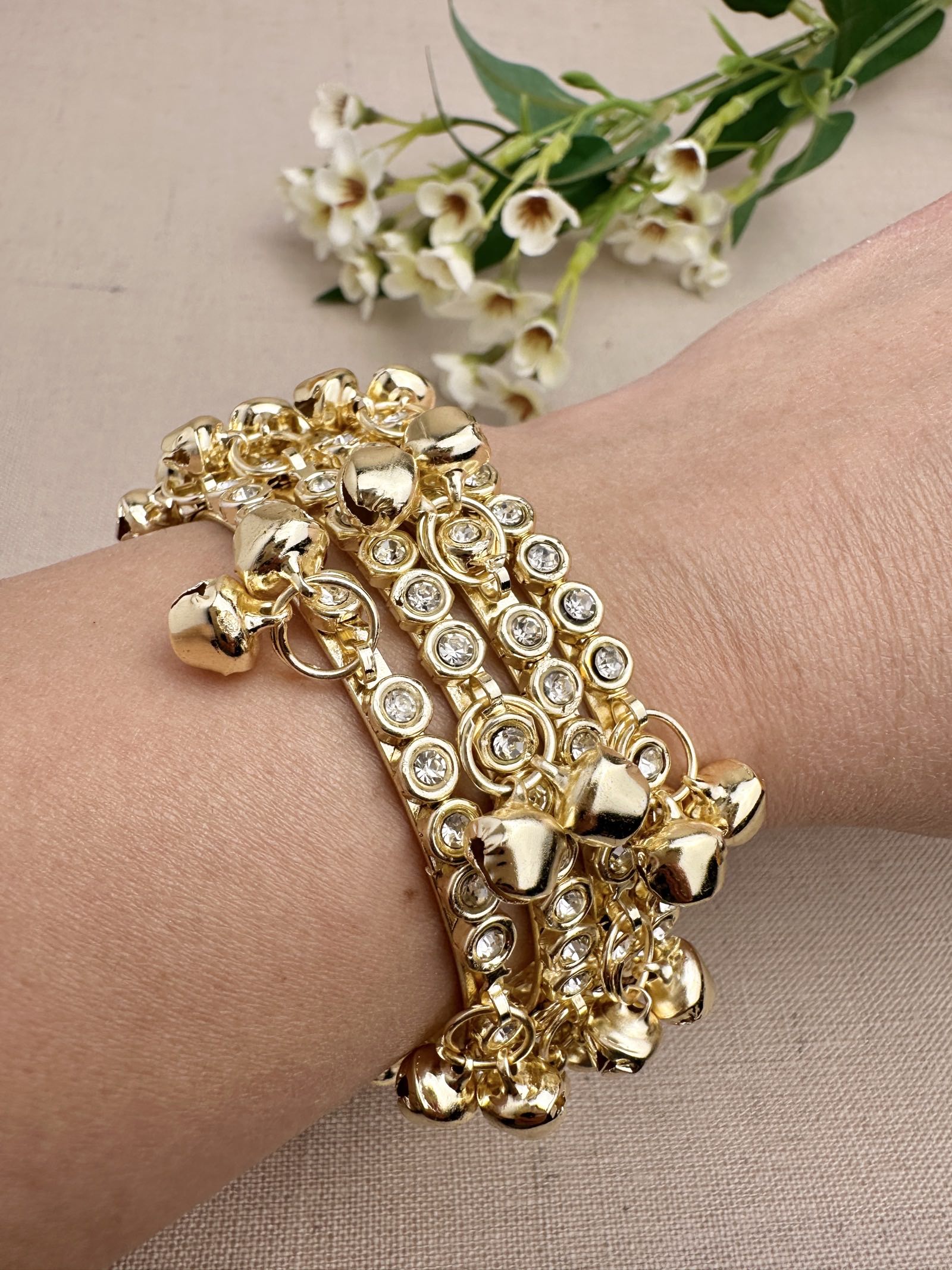 Four gold tone stone ghungroo bangles styled together on wrist