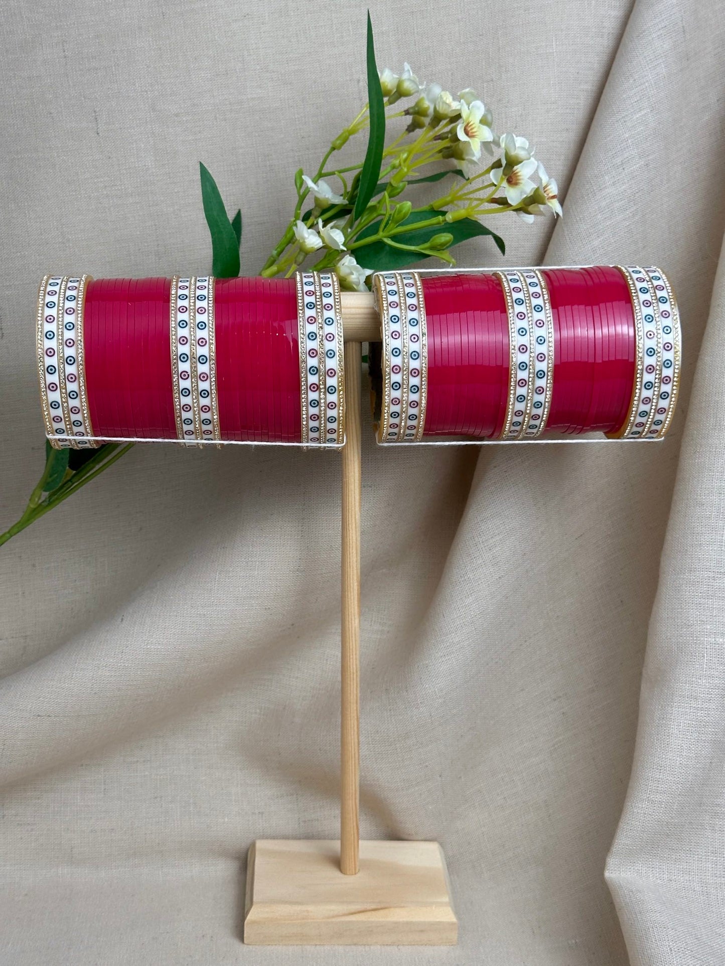 Complete hot pink Punjabi bridal chooda set for both arms displayed on a wooden stand.
