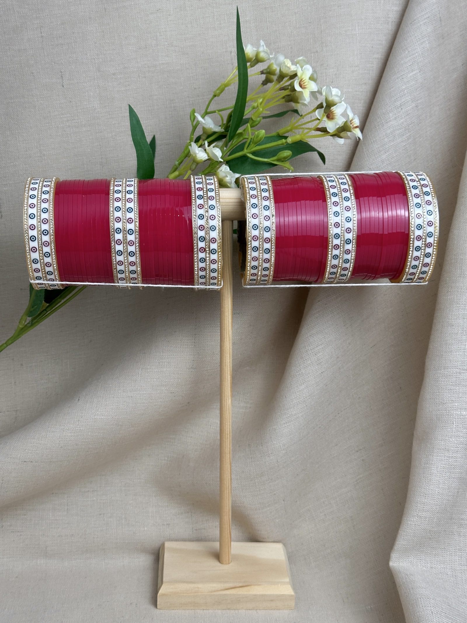 Complete hot pink Punjabi bridal chooda set for both arms displayed on a wooden stand.