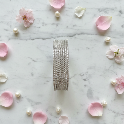 Sophia AD bangle set vertical flat lay with flower petals and pearls on marble