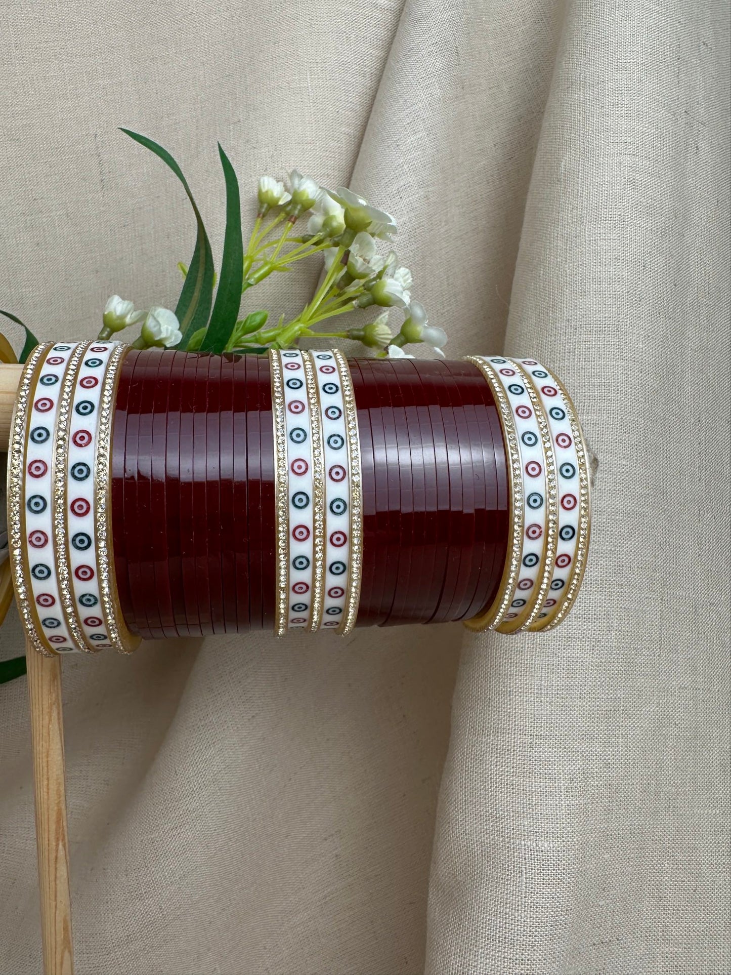 Close-up of maroon bridal bangles with white patterned bangles, stone borders and gold-toned detailing.