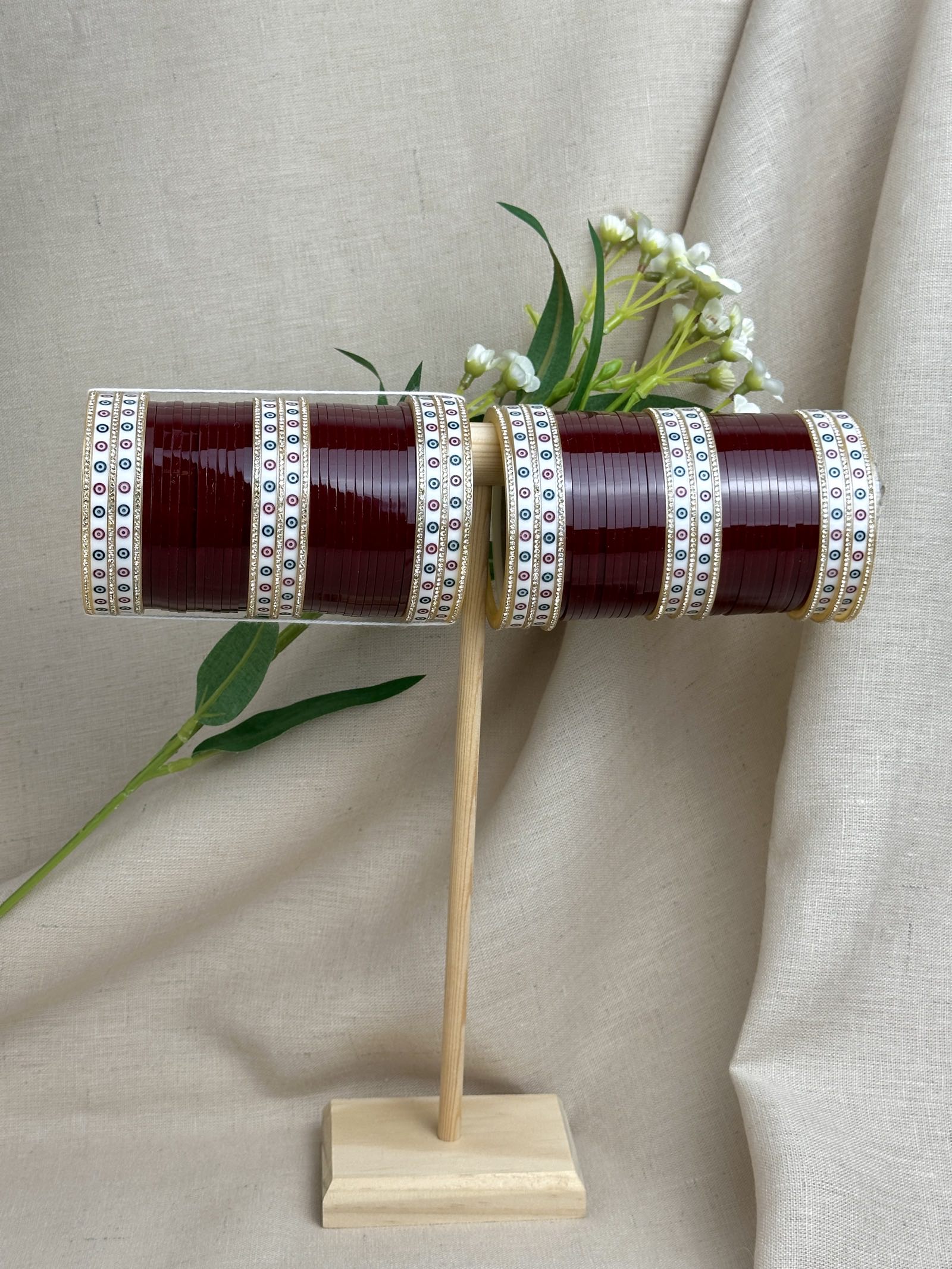 Complete maroon Punjabi bridal chooda set for both arms displayed on a wooden stand.