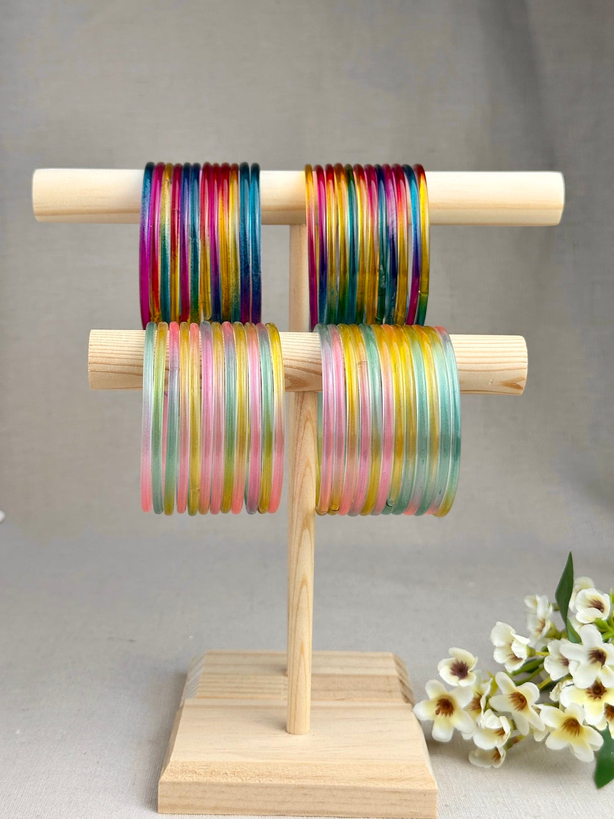 Mayra Multicolor Jelly Bangles in dark and pastel rainbow shades displayed on a wooden bangle stand by Riwaaz by SG.