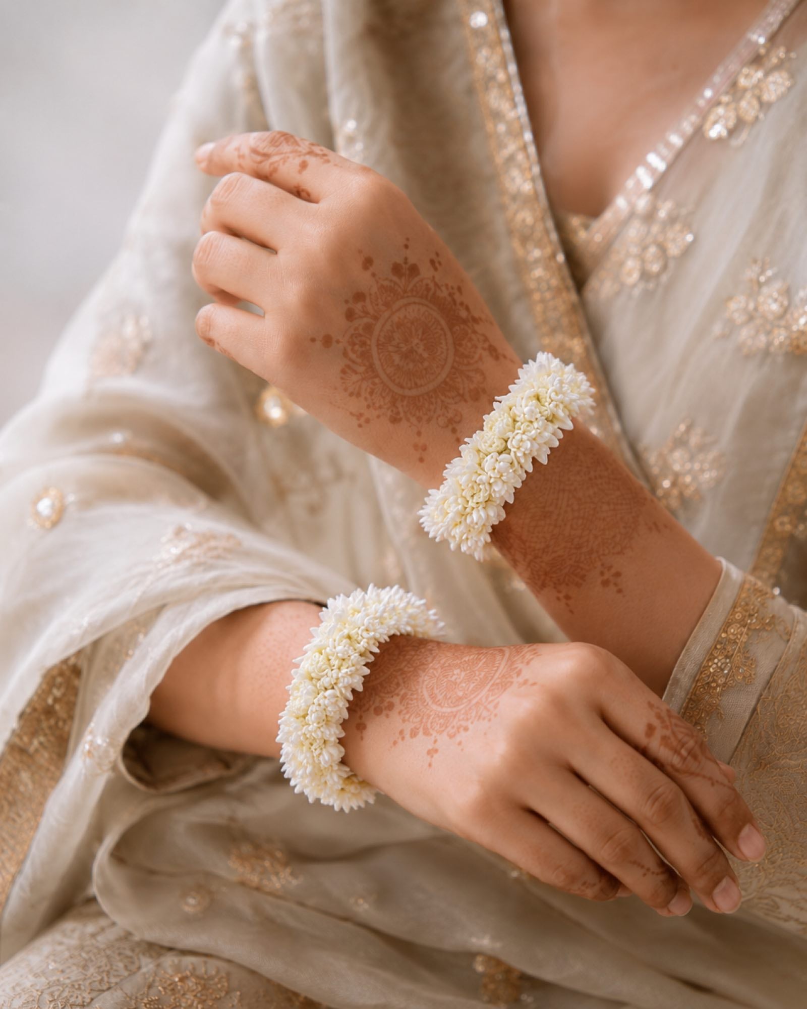 Styling reference showing an off-white gajra pair worn on the wrists with mehndi.