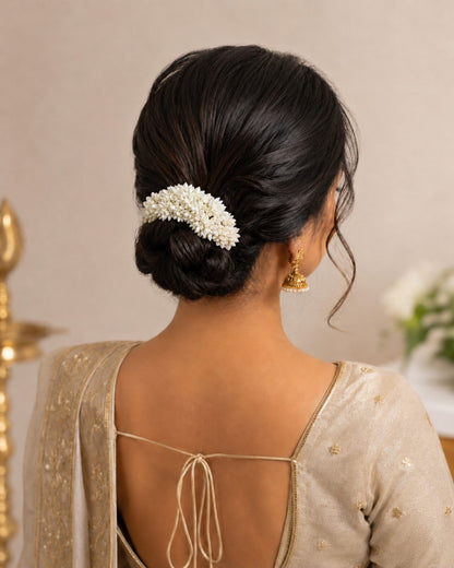 Styling reference showing an off-white gajra worn around a traditional hair bun.