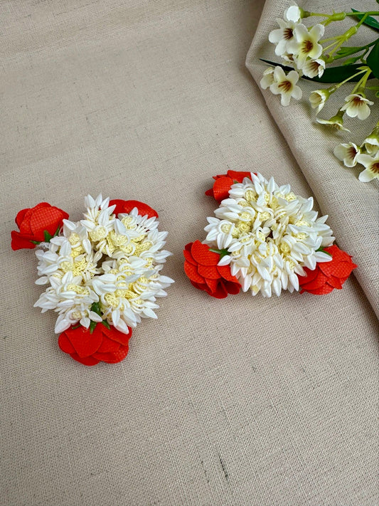 Pair of red and off-white reusable artificial gajras displayed on cream fabric.
