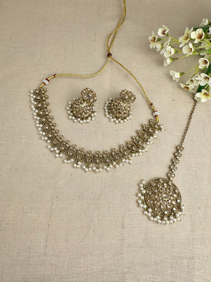 Flat-lay view of Saanjh champagne necklace, jhumki and tikka set