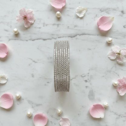 Sophia AD bangle set vertical flat lay with flower petals and pearls on marble